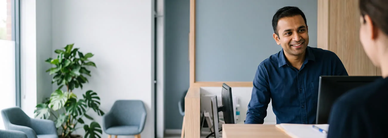 A dentist chatting with a smiling patient at the front desk